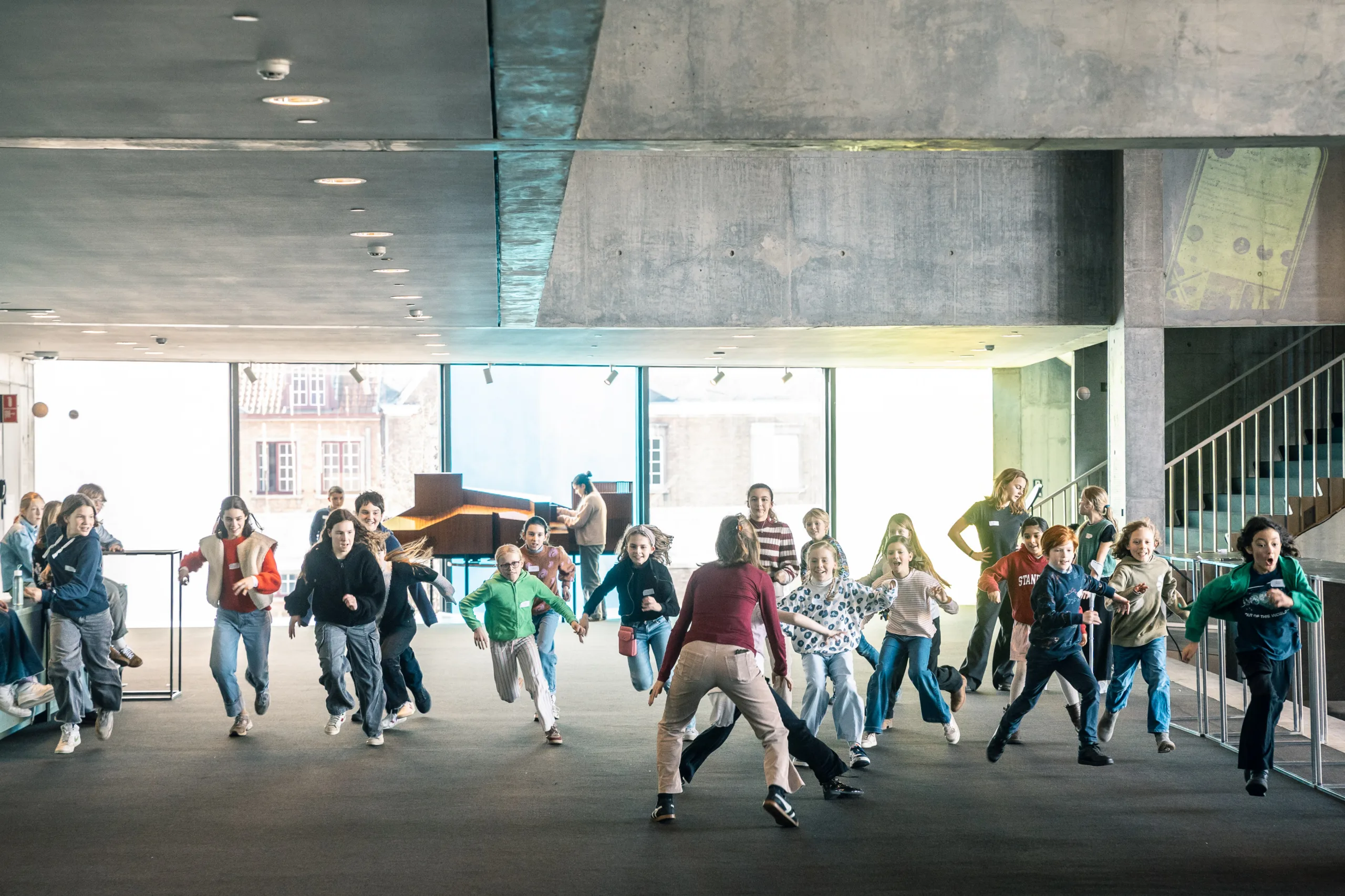 Een vijftiental kinderen spelen een spelletje waarbij ze aan het lopen zijn, met hun gezichten naar ons toe